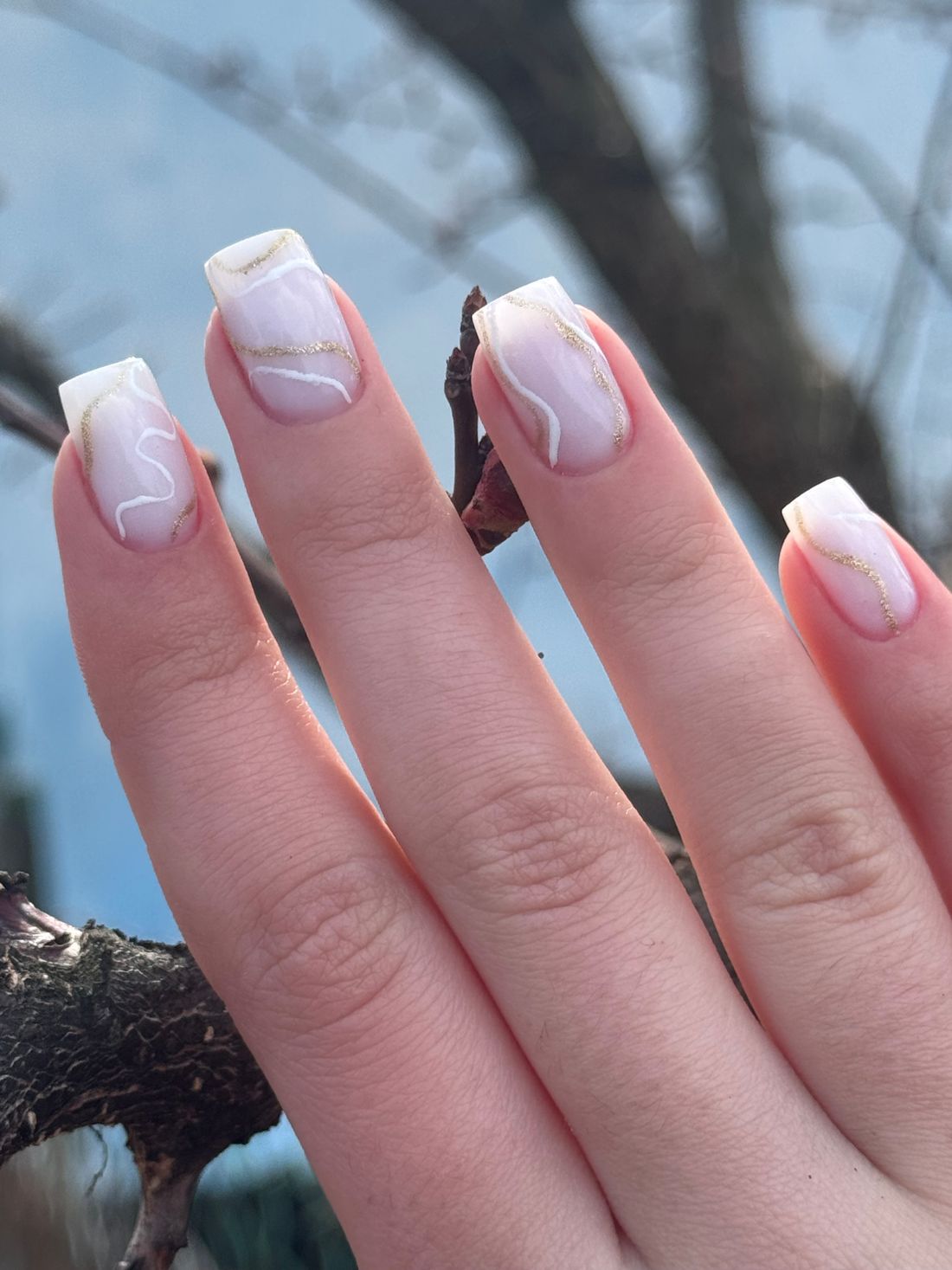 Hand met vierkante nagels met een witte French-rand en fijne marmerlijntjes